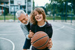© Marko Geber - Grandfather teaching his grandson how to play basketball at an outdoor basketball court