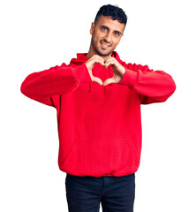 Sticker - Young hispanic man wearing casual clothes smiling in love showing heart symbol and shape with hands. romantic concept.