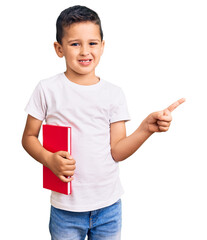 Wall Mural - Little cute boy kid reading a book smiling happy pointing with hand and finger to the side