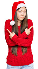 Wall Mural - Young chinese woman wearing christmas hat pointing to both sides with fingers, different direction disagree