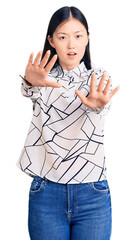 Canvas Print - Young beautiful chinese woman wearing casual shirt doing stop gesture with hands palms, angry and frustration expression