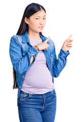 Sticker - Young beautiful chinese woman pregnant expecting baby pointing aside worried and nervous with both hands, concerned and surprised expression