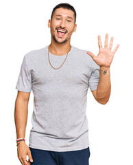 Canvas Print - Handsome man with tattoos wearing 90s style showing and pointing up with fingers number five while smiling confident and happy.