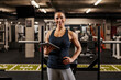 © dusanpetkovic1 - A female trainer is standing with a tablet in a gym.