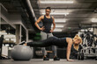© Dusan Petkovic - A sportswoman is exercising planks with fitness ball while her female coach is looking at her.