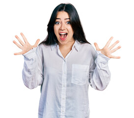 Wall Mural - Beautiful hispanic woman wearing casual white shirt celebrating crazy and amazed for success with arms raised and open eyes screaming excited. winner concept