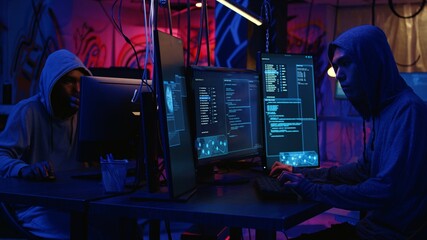Hackers in dark abandoned warehouse using phishing technique that tricks users into revealing sensitive information. Rogue developers stealing passwords from low security systems, dolly in shot