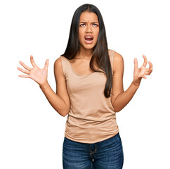 Poster - Beautiful hispanic woman wearing casual clothes crazy and mad shouting and yelling with aggressive expression and arms raised. frustration concept.