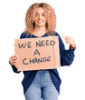 © Krakenimages.com - Young blonde woman with curly hair holding we need a change banner smiling happy pointing with hand and finger