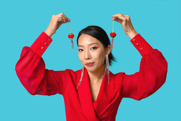 Beautiful young Asian woman with decorative lanterns on blue background. Chinese New Year celebration