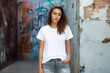 © NaphakStudio - Portrait of confident young woman wearing white blank t-shirt, Mockup shirt for design.