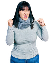 Poster - Young hispanic plus size woman wearing winter scarf angry and mad raising fists frustrated and furious while shouting with anger. rage and aggressive concept.