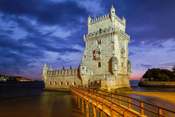 Wall Mural - Belem Tower or Tower of St Vincent - famous tourist landmark of Lisboa and tourism attraction - on the bank of the Tagus River (Tejo) after sunset in dusk twilight with dramatic sky. Lisbon, Portugal