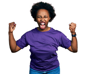 Poster - African american woman with afro hair wearing casual purple t shirt angry and mad raising fists frustrated and furious while shouting with anger. rage and aggressive concept.