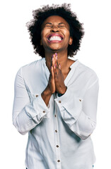 Poster - African american woman with afro hair wearing casual white t shirt begging and praying with hands together with hope expression on face very emotional and worried. begging.