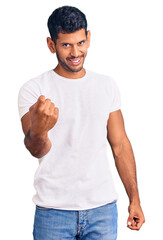 Sticker - Young latin man wearing casual clothes beckoning come here gesture with hand inviting welcoming happy and smiling