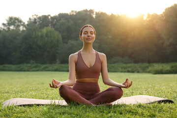 Canvas Print - Beautiful young woman practicing Padmasana on yoga mat outdoors. Lotus pose