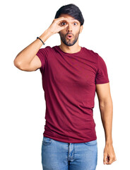 Canvas Print - Handsome hispanic man wearing casual clothes doing ok gesture shocked with surprised face, eye looking through fingers. unbelieving expression.