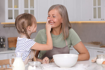 Wall Mural - Happy grandmother with her granddaughter having fun while cooking together in kitchen