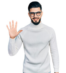 Wall Mural - Young arab man with beard wearing elegant turtleneck sweater and glasses showing and pointing up with fingers number five while smiling confident and happy.