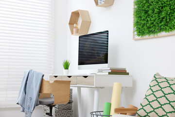 Poster - Green artificial plant wall panel and desk with computer in light room. Interior design