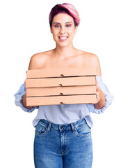 Poster - Young beautiful woman with pink hair holding delivery pizza box looking positive and happy standing and smiling with a confident smile showing teeth