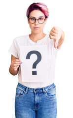 Poster - Young beautiful woman with pink hair holding question mark with angry face, negative sign showing dislike with thumbs down, rejection concept