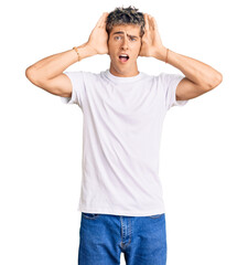 Wall Mural - Young handsome man wearing casual white tshirt smiling cheerful playing peek a boo with hands showing face. surprised and exited