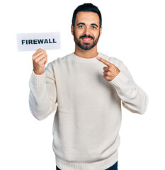 Sticker - Young hispanic man with beard holding firewall banner smiling happy pointing with hand and finger