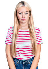 Wall Mural - Beautiful blonde woman wearing casual striped t shirt relaxed with serious expression on face. simple and natural looking at the camera.