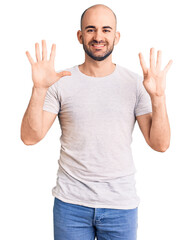 Wall Mural - Young handsome man wearing casual t shirt showing and pointing up with fingers number nine while smiling confident and happy.