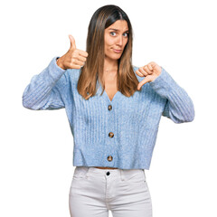 Wall Mural - Young woman wearing casual clothes doing thumbs up and down, disagreement and agreement expression. crazy conflict