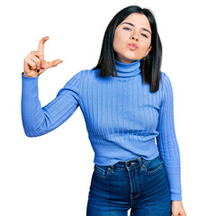 Canvas Print - Young brunette woman with blue eyes doing size gesture holding invisible object looking at the camera blowing a kiss being lovely and sexy. love expression.