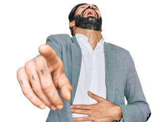 Poster - Young hispanic man wearing business clothes laughing at you, pointing finger to the camera with hand over body, shame expression