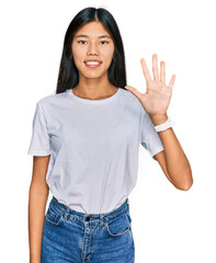 Canvas Print - Beautiful young asian woman wearing casual white t shirt showing and pointing up with fingers number five while smiling confident and happy.