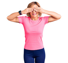 Poster - Young blonde woman wearing sportswear covering eyes with hands smiling cheerful and funny. blind concept.