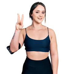 Wall Mural - Young hispanic woman wearing sportswear showing and pointing up with fingers number three while smiling confident and happy.