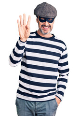 Sticker - Middle age handsome man wearing burglar mask showing and pointing up with fingers number four while smiling confident and happy.