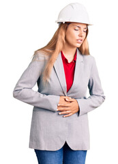 Canvas Print - Beautiful young woman wearing architect hardhat with hand on stomach because nausea, painful disease feeling unwell. ache concept.