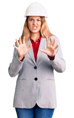 Canvas Print - Beautiful young woman wearing architect hardhat disgusted expression, displeased and fearful doing disgust face because aversion reaction. with hands raised