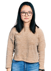 Wall Mural - Young chinese woman wearing casual sweater and glasses relaxed with serious expression on face. simple and natural looking at the camera.