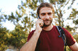 © fotofabrika - Male hiker with a backpack is talking on the phone in the countryside