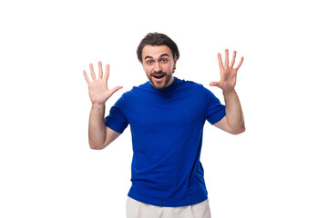 Wall Mural - young surprised handsome european man with black hair and beard dressed in a blue t-shirt on a white background with copy space