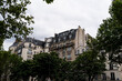Parisian facade on a cloudy day, framed by trees