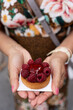 unidentified woman in colorful dress holding up french pastry, fruit tart, with beautiful raspberries