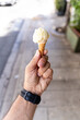 Man holding beautiful miniature ice-cream italian gelato on sugar cone, in front of ice cream store, Italy
