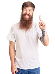 Poster - Handsome young red head man with long beard wearing casual white tshirt showing and pointing up with finger number one while smiling confident and happy.