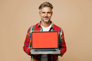 Adult IT man wear red shirt white t-shirt casual clothes hold use work on laptop pc computer with blank screen workspace area isolated on plain pastel light beige color background. Lifestyle concept.