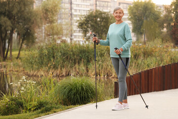 Sticker - Senior woman performing Nordic walking outdoors, space for text