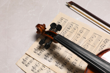 Wall Mural - Violin, bow and music sheets on grey marble table. Space for text